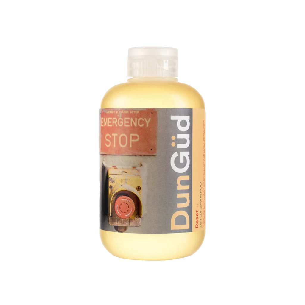 Fles DunGüd Reset Detox Shampoo met industrieel noodstopmotief op het etiket.