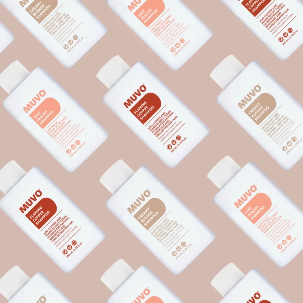 Afbeelding met meerdere flessen MUVO shampoo in verschillende varianten op een beige achtergrond.