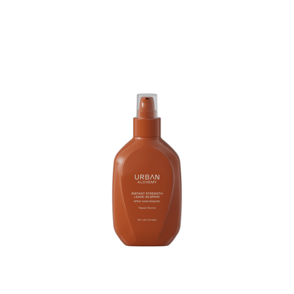Bruine fles Urban Alchemy Instant Strength Leave-In Spray met pompverstuiver, tegen een zwarte achtergrond.