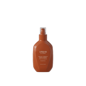 Bruine fles Urban Alchemy Instant Strength Leave-In Spray met pompverstuiver, tegen een zwarte achtergrond.